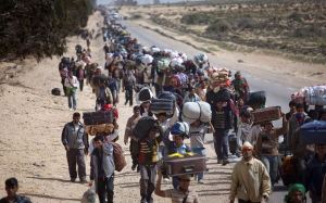 FOR USE AS DESIRED, YEAR END PHOTOS - FILE -In this March 4, 2011 file photo, men from Bangladesh, who used to work in Libya but recently fled the unrest, walk with their belongings alongside a road, as they head to a refugee camp after crossing the Tunisia-Libyan border, in Ras Ajdir, Tunisia. (AP Photo/Emilio Morenatti, File)
